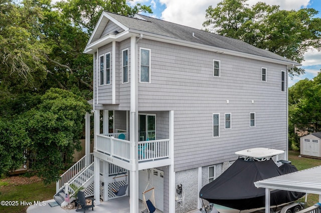 rear view of house with a garage, a balcony, and a storage shed