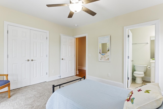 bedroom with connected bathroom, light colored carpet, ceiling fan, and a closet