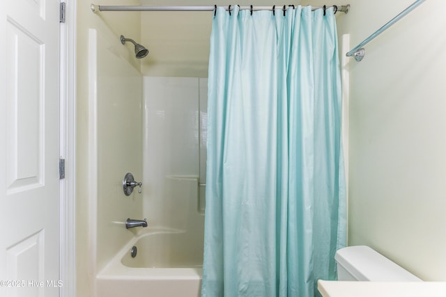 bathroom featuring shower / bathtub combination with curtain and toilet