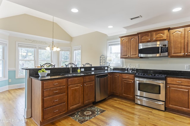 kitchen with vaulted ceiling, sink, dark stone counters, light hardwood / wood-style floors, and stainless steel appliances