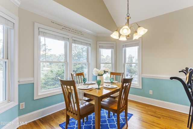 dining space with lofted ceiling, crown molding, an inviting chandelier, and light wood-type flooring