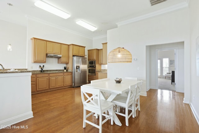 kitchen with pendant lighting, crown molding, light hardwood / wood-style flooring, and appliances with stainless steel finishes