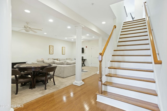 stairs featuring hardwood / wood-style flooring, decorative columns, and ceiling fan