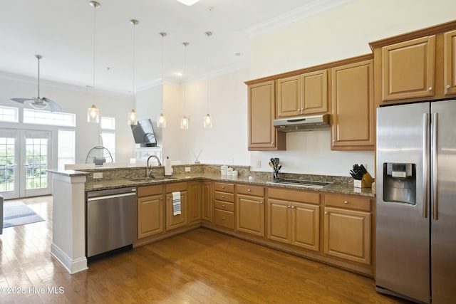 kitchen with sink, dark stone counters, hanging light fixtures, stainless steel appliances, and crown molding