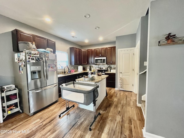 kitchen featuring backsplash, stainless steel appliances, light hardwood / wood-style floors, and a kitchen island