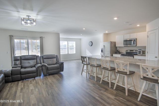 kitchen featuring white cabinetry, light stone countertops, a breakfast bar, and appliances with stainless steel finishes