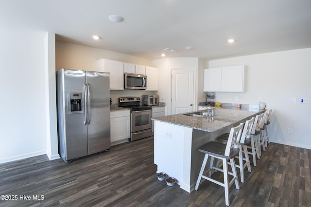 kitchen with white cabinetry, sink, a breakfast bar area, light stone counters, and stainless steel appliances