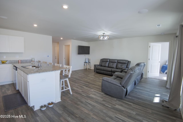 kitchen featuring dark hardwood / wood-style floors, a breakfast bar, white cabinetry, sink, and light stone counters