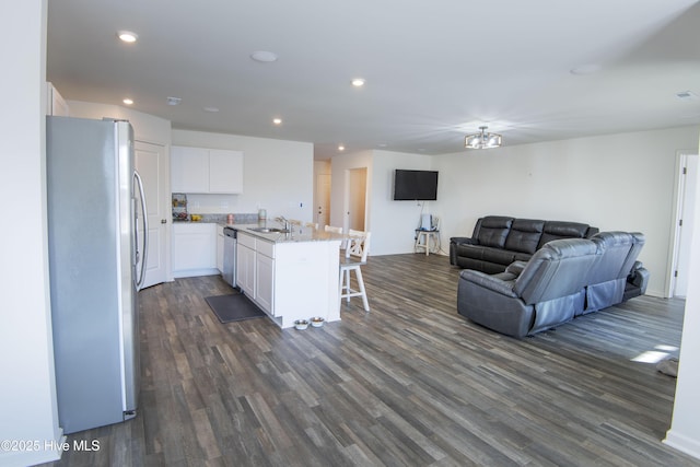 kitchen featuring appliances with stainless steel finishes, an island with sink, sink, white cabinets, and a kitchen breakfast bar