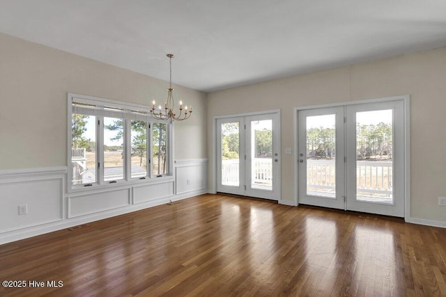 unfurnished dining area featuring a chandelier and dark hardwood / wood-style flooring