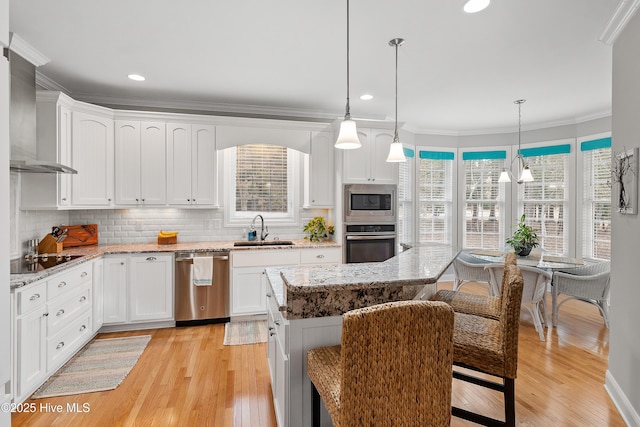 kitchen with appliances with stainless steel finishes, a sink, white cabinetry, and decorative light fixtures