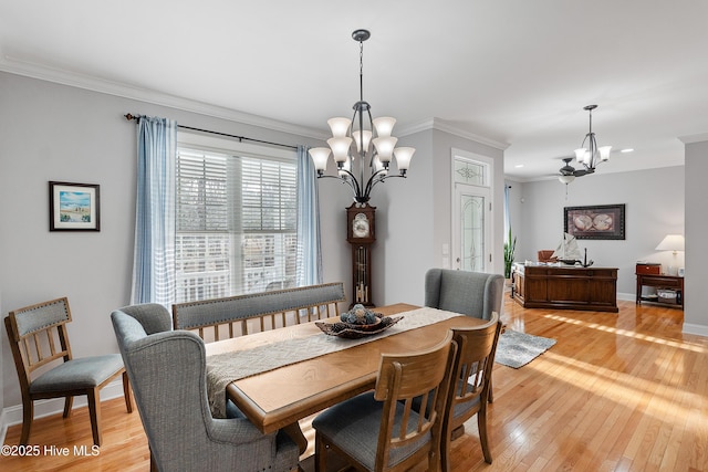 dining area with light wood-style floors, baseboards, ornamental molding, and a notable chandelier