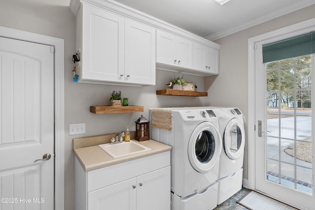 laundry area featuring crown molding, cabinet space, a sink, and washing machine and clothes dryer