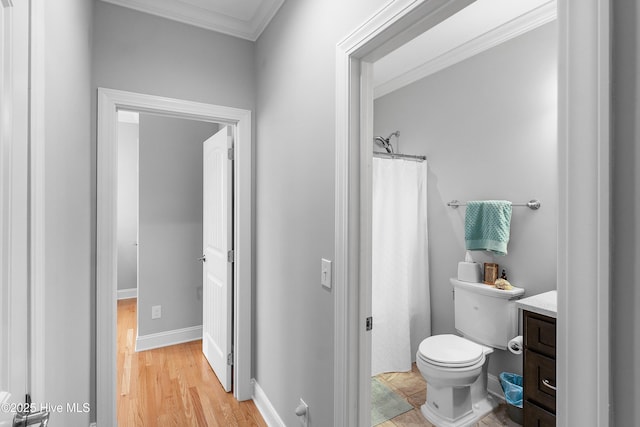 full bathroom featuring toilet, ornamental molding, vanity, wood finished floors, and baseboards