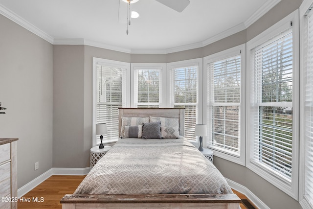 bedroom featuring ornamental molding, multiple windows, baseboards, and wood finished floors