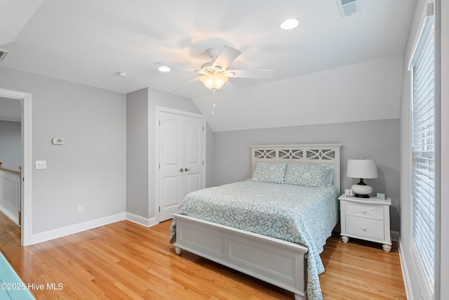 bedroom with vaulted ceiling, wood finished floors, visible vents, and baseboards