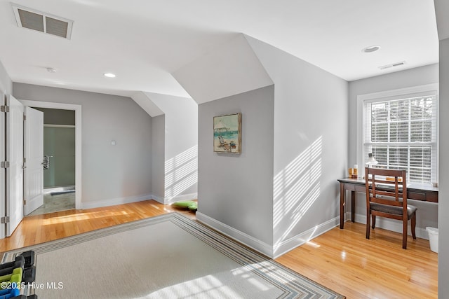 hall featuring visible vents, baseboards, and wood finished floors