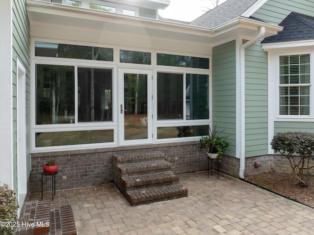 exterior space with a shingled roof and a patio