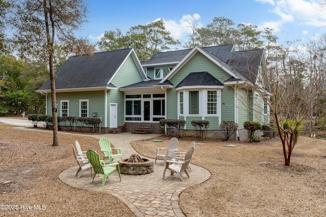 back of house featuring entry steps, an outdoor fire pit, roof with shingles, and a patio