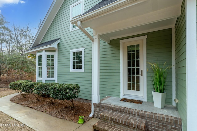 doorway to property with a shingled roof