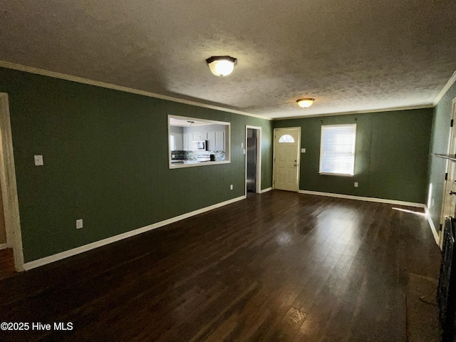 spare room featuring baseboards, dark wood-type flooring, ornamental molding, and a textured ceiling