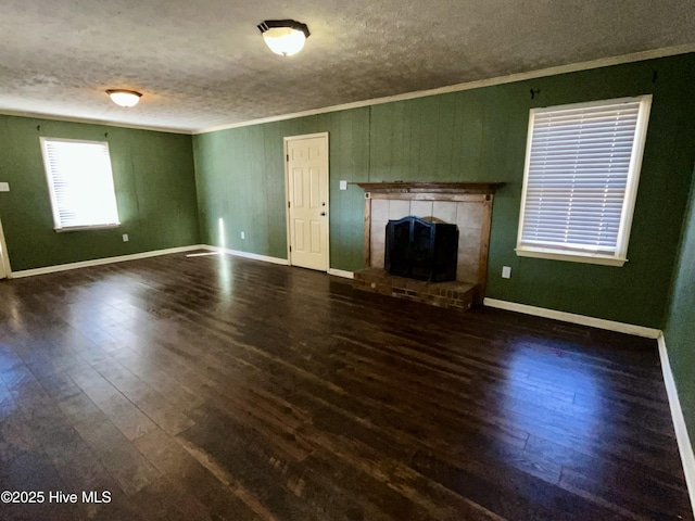 unfurnished living room with a fireplace with raised hearth, a textured ceiling, wood finished floors, and ornamental molding