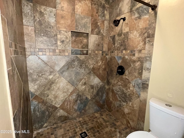 bathroom with toilet and a tile shower