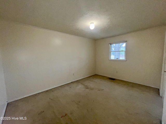 spare room featuring visible vents, a textured ceiling, and carpet