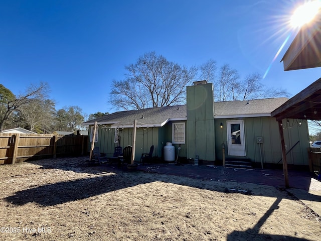 rear view of house featuring entry steps, a patio, fence, and board and batten siding