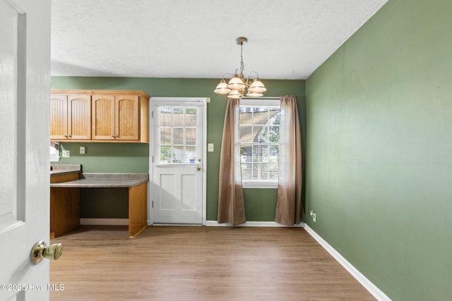 entryway with a chandelier, a textured ceiling, and light wood-type flooring