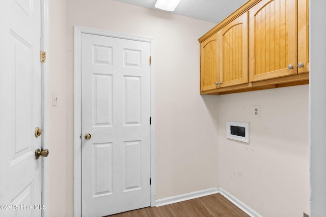 clothes washing area with cabinets, dark hardwood / wood-style floors, hookup for an electric dryer, and a textured ceiling