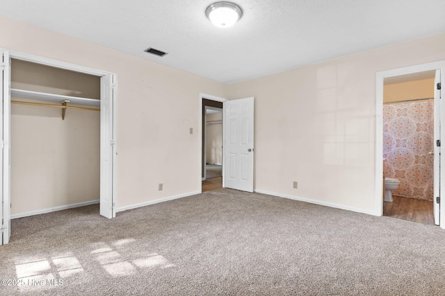 unfurnished bedroom with carpet floors, ensuite bath, and a closet