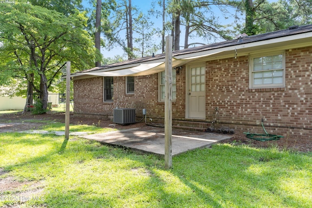 back of property with cooling unit, a patio area, and a lawn