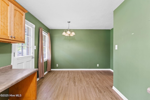 unfurnished dining area with a notable chandelier and light hardwood / wood-style flooring