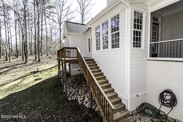 exterior space featuring stairway and roof with shingles