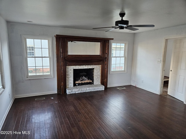 unfurnished living room featuring dark hardwood / wood-style flooring, a wealth of natural light, a fireplace, and ceiling fan