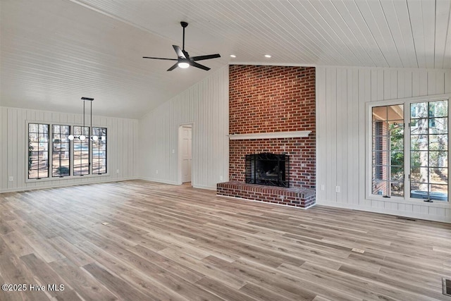 unfurnished living room with a fireplace, vaulted ceiling, and wood finished floors