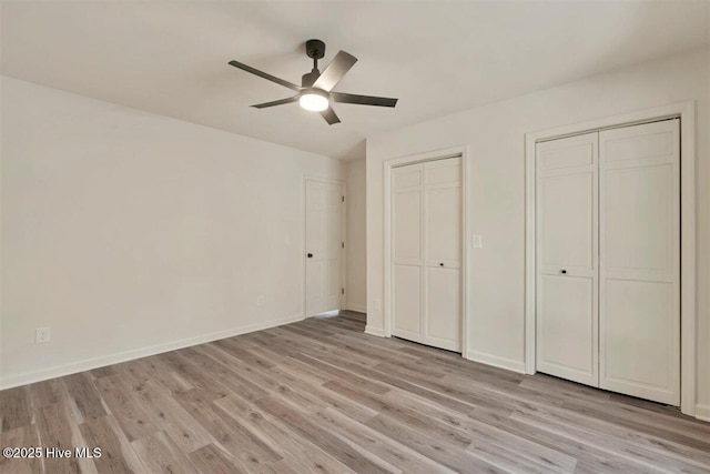 unfurnished bedroom featuring ceiling fan, light wood finished floors, two closets, and baseboards