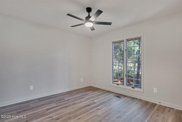 spare room with ceiling fan, wood finished floors, visible vents, and baseboards