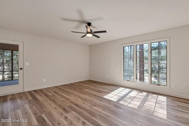 spare room featuring ceiling fan, baseboards, and wood finished floors