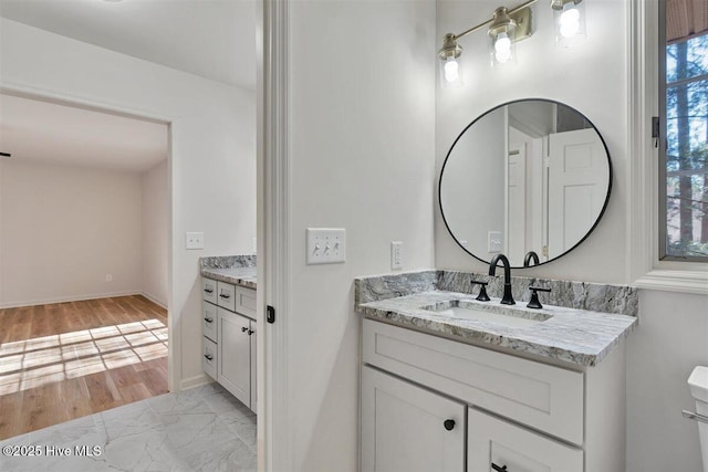 bathroom with toilet, marble finish floor, vanity, and baseboards