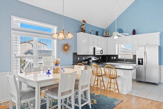 kitchen featuring sink, a breakfast bar area, white cabinetry, decorative light fixtures, and appliances with stainless steel finishes