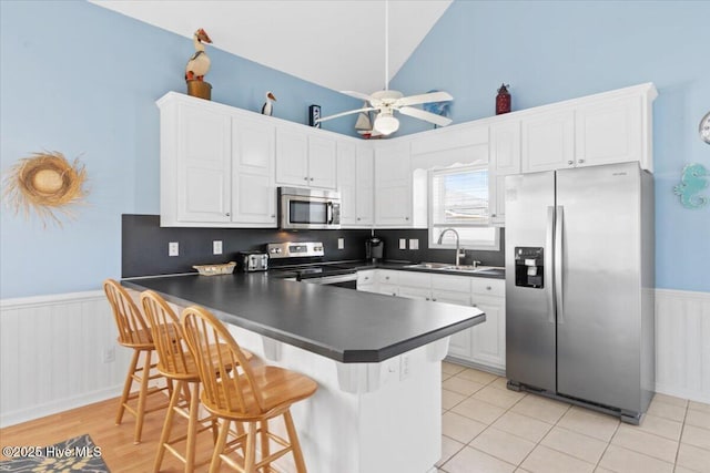 kitchen with sink, a kitchen breakfast bar, stainless steel appliances, white cabinets, and kitchen peninsula