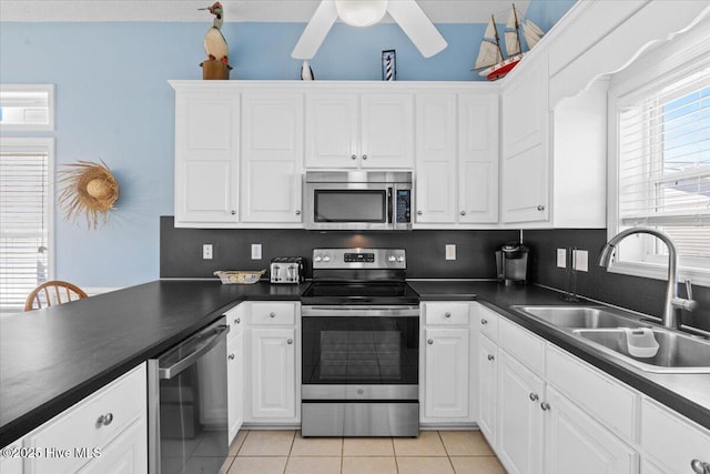 kitchen with stainless steel appliances, white cabinetry, sink, and light tile patterned floors