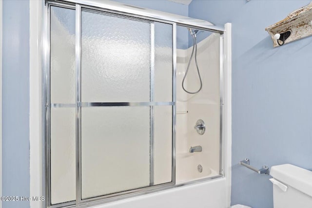 bathroom with combined bath / shower with glass door and toilet