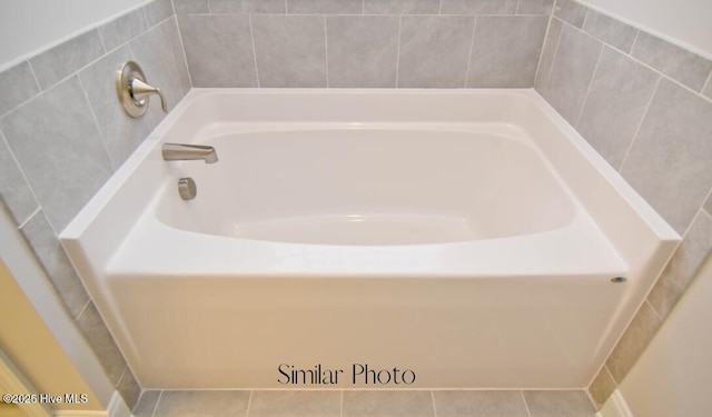 bathroom with a tub to relax in and tile patterned flooring