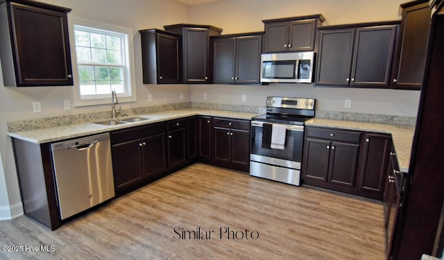 kitchen with appliances with stainless steel finishes, sink, light hardwood / wood-style floors, and dark brown cabinets