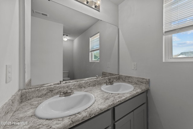 bathroom with toilet, vanity, and a healthy amount of sunlight