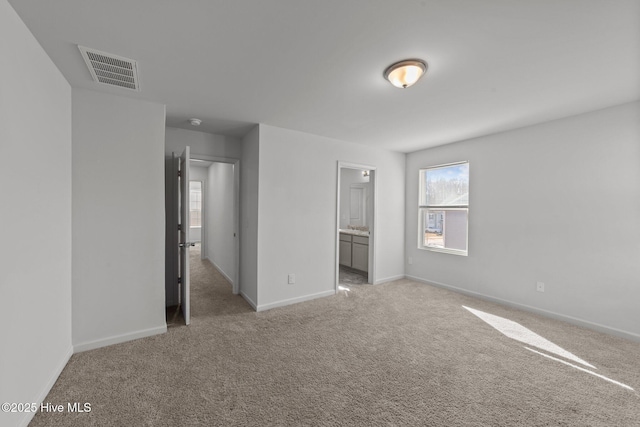 unfurnished bedroom featuring light colored carpet and ensuite bathroom