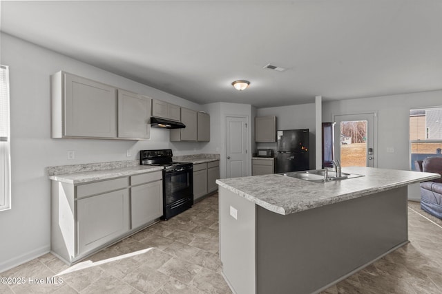 kitchen featuring gray cabinets, an island with sink, sink, and black appliances